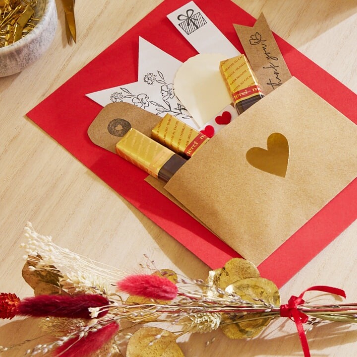 Carte faite main avec enveloppe collée. Elle contient des bâtonnets de chocolat merci