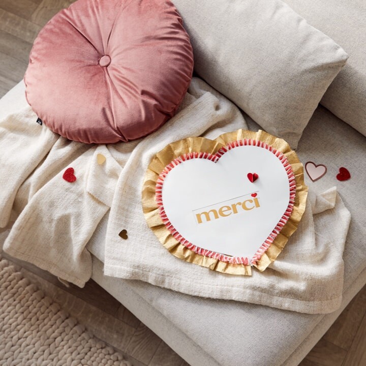 Cœur en papier, avec des volants en papier crépon à l'extérieur, au centre : « Merci »