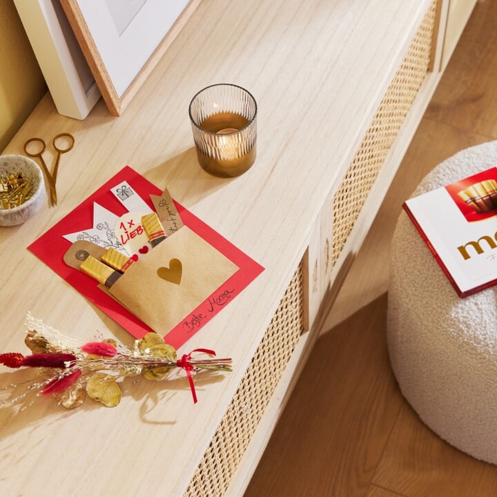 Gebastelte Karte mit aufgeklebtem Umschlag. Darin stecken merci Schokoladen-Stäbchen. Darunter steht in Handschrift: Beste Mama