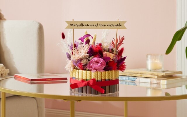 Une boîte en forme de cœur, décorée à l'extérieur avec « merci Finest Selection », à l'intérieur avec des fleurs et un petit drapeau en papier portant l'inscription : « Merveilleusement bien ensemble »